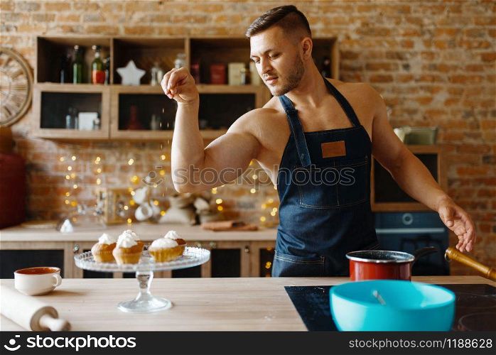 Nude husband in apron cooking dessert with cream on the kitchen. Naked male person preparing breakfast at home, food preparation without clothes. Nude husband in apron cooking dessert with cream