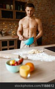 Nude man cooking dessert on the kitchen. Naked male person preparing breakfast at home, food preparation. Nude man cooking dessert on the kitchen