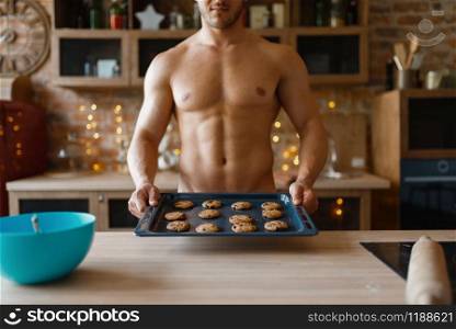 Nude man cooking pastry on the kitchen. Naked male person preparing breakfast at home, food preparation without clothes. Nude man cooking pastry on the kitchen