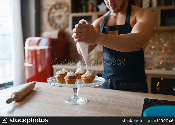 Nude man in apron cooking dessert on the kitchen. Naked male person preparing breakfast at home, food preparation without clothes