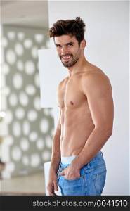 nude shirtles handsome young man in jeans posing at modern home indoors