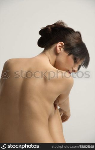 Nude woman in a lovely beauty portrait , showing her back and looking down sweetness . she has natural skin
