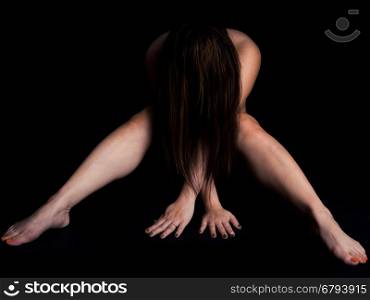 Nude woman nude with hair covering face on black background