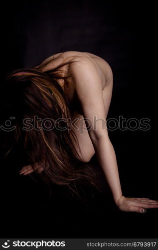 Nude woman nude with hair covering face on black background