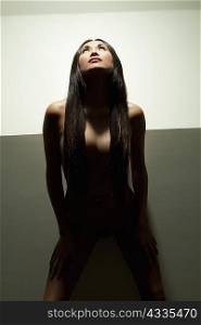 Nude woman standing under spotlight