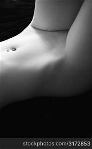 Nude young adult Caucasian female waist and thighs with pierced belly button.