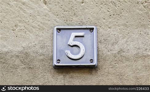 Number five, detail of a metal plate in the street with the number five digit signal