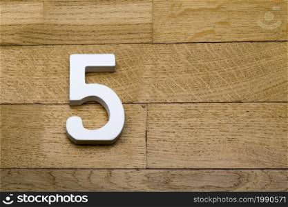 Number five on the wooden parquet floor in the background.. The figures are five on the wooden, parquet floor.