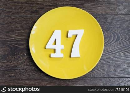 Number forty seven on the yellow plate and brown background.. Number forty seven on the yellow plate.