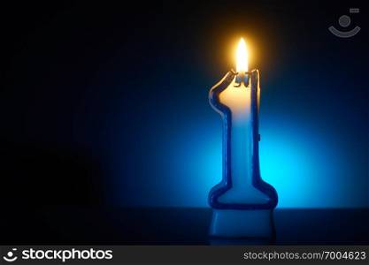 Number One - Burning birthday candle on blue background