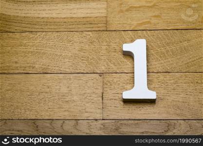 Number one on a wooden, parquet floor as a background.. Number one on the wooden, parquet floor.