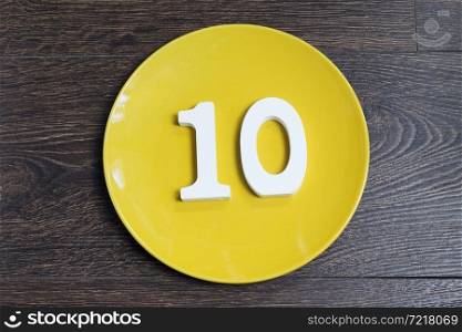 Number ten on a yellow plate and brown background.. Number ten on a yellow plate.