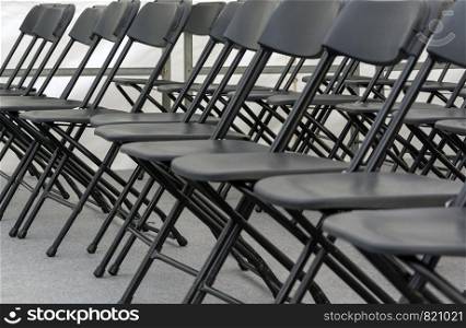 numerous folding chairs arranged in a row in a conference room.