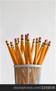 Numerous orange HB lead pencils in holder, on white background.