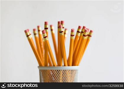 Numerous orange HB lead pencils in holder, on white background.