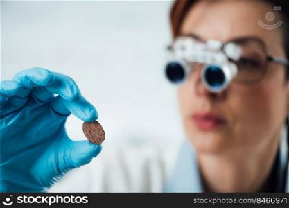 Numismatics expert examines a collection of coins, using magnifying goggles. Numismatics Expert Examines a Collection of Coins