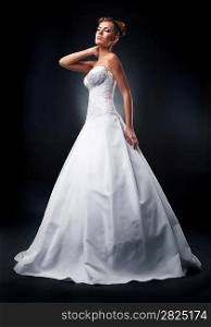 Nuptials -pretty young bride blonde standing on podium in wedding white dress - studio shot
