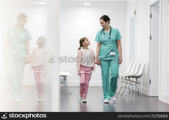 Nurse and girl patient walking in corridor at hospital