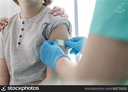 Nurse applying bandage on boy arm at hospital