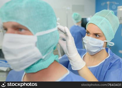 nurse assiting to secure mask on colleague