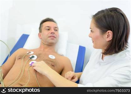 nurse attching pads to patients chest to monitor his heart