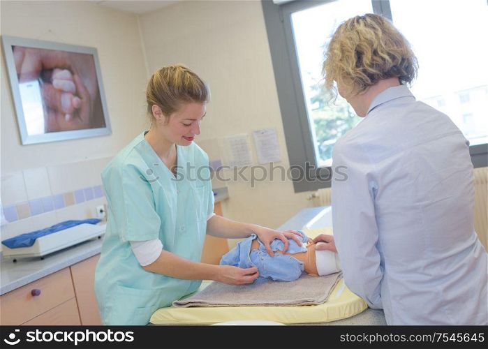 nurse changing babys nappy in hospital