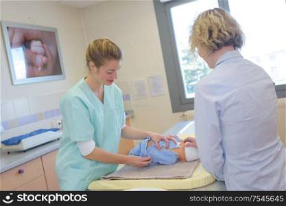 nurse changing babys nappy in hospital
