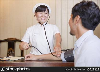 Nurse Checking Businessman&rsquo;s Blood Pressure