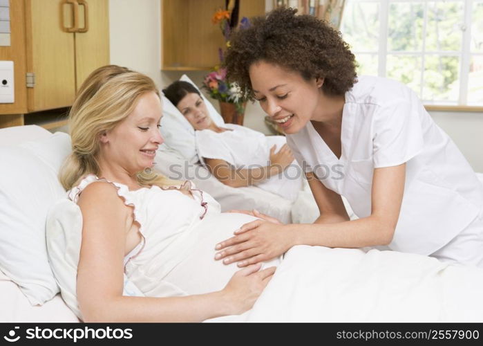 Nurse checking pregnant woman&acute;s belly and smiling