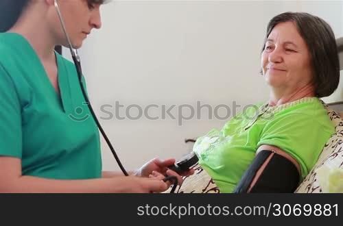Nurse checking senior woman blood pressure at home. Focus on patient.