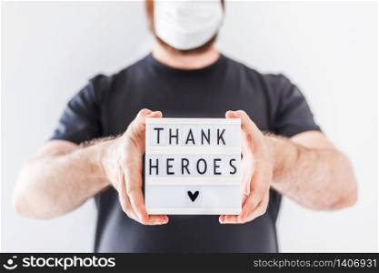 Nurse day concept. Man hands holding lightbox with Thank heroes text thanking doctors, nurses and medical staff working in hospitals during coronavirus COVID-19 pandemics.