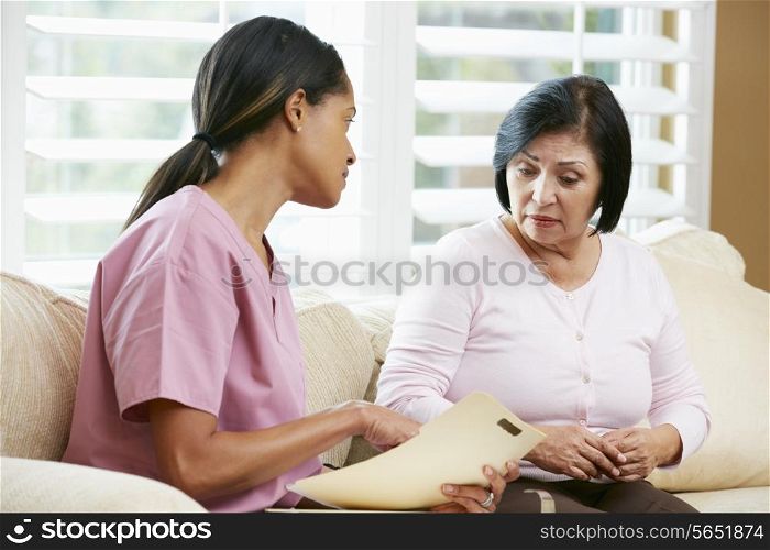 Nurse Discussing Records With Senior Female Patient During Home Visit