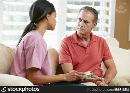 Nurse Discussing Records With Senior Male Patient During Home Visit