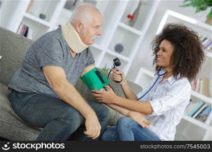 nurse examining blood pressure of senior man at home