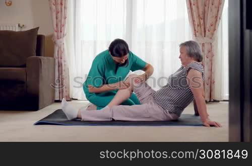 Nurse giving leg massage to senior woman in a retirement home. Physiotherapist nurse helping an elderly women physical rehabilitation at home. Slow motion hand held movement