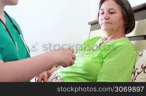 Nurse giving to senior woman the pill capsules from the box. Focus on patient.
