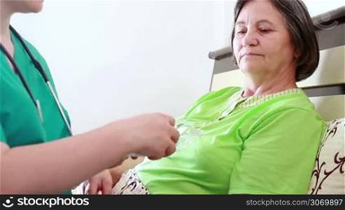 Nurse giving to senior woman the pill capsules from the box. Focus on patient.