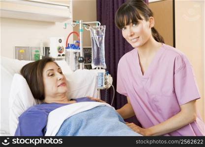 Nurse Helping Senior Woman Lying In Hospital Bed