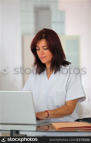 Nurse in scrubs using a laptop