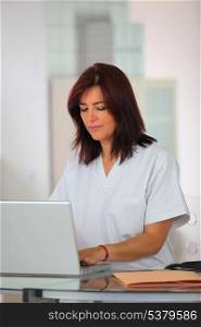 Nurse in scrubs using a laptop