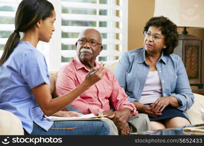 Nurse Making Notes During Home Visit With Senior Couple