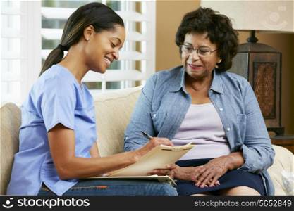 Nurse Making Notes During Home Visit With Senior Female Patient
