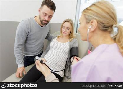 nurse measuring blood pressure of pregnant woman