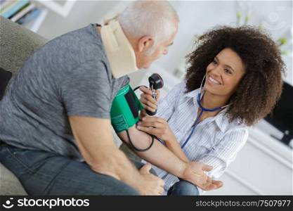 nurse measuring blood pressure of senior at home