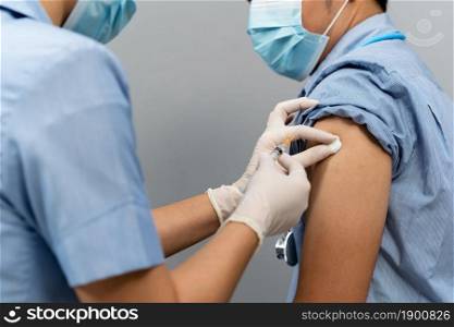Nurse or Medical professionals holding syringe and using cotton before make injection to dortor in a mask. Covid-19 or coronavirus vaccine