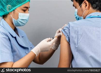 Nurse or Medical professionals holding syringe and using cotton before make injection to dortor in a mask. Covid-19 or coronavirus vaccine