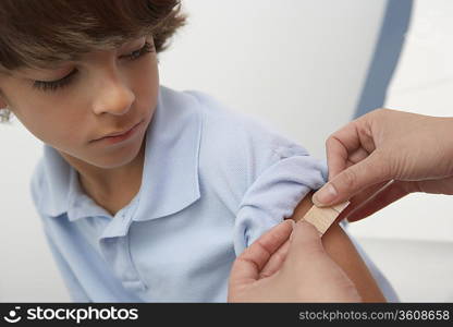 Nurse placing bandage on boy&acute;s arm,close up