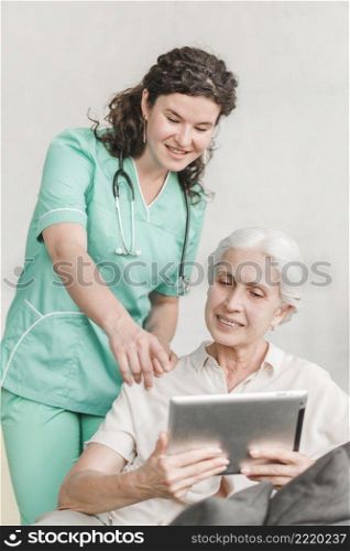 nurse pointing screen showing something her patient digital tablet