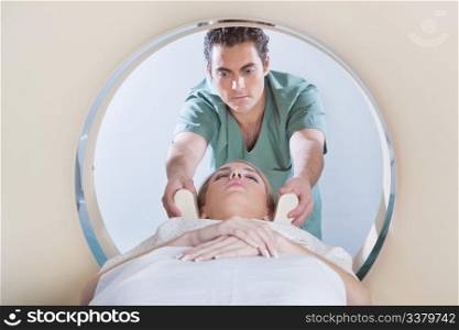 Nurse preparing young woman for CT scan test