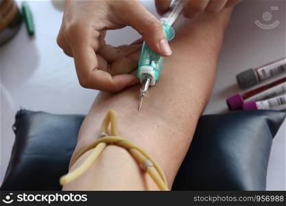 nurse pricking needle in artery arm to keep blood sample for lab testing